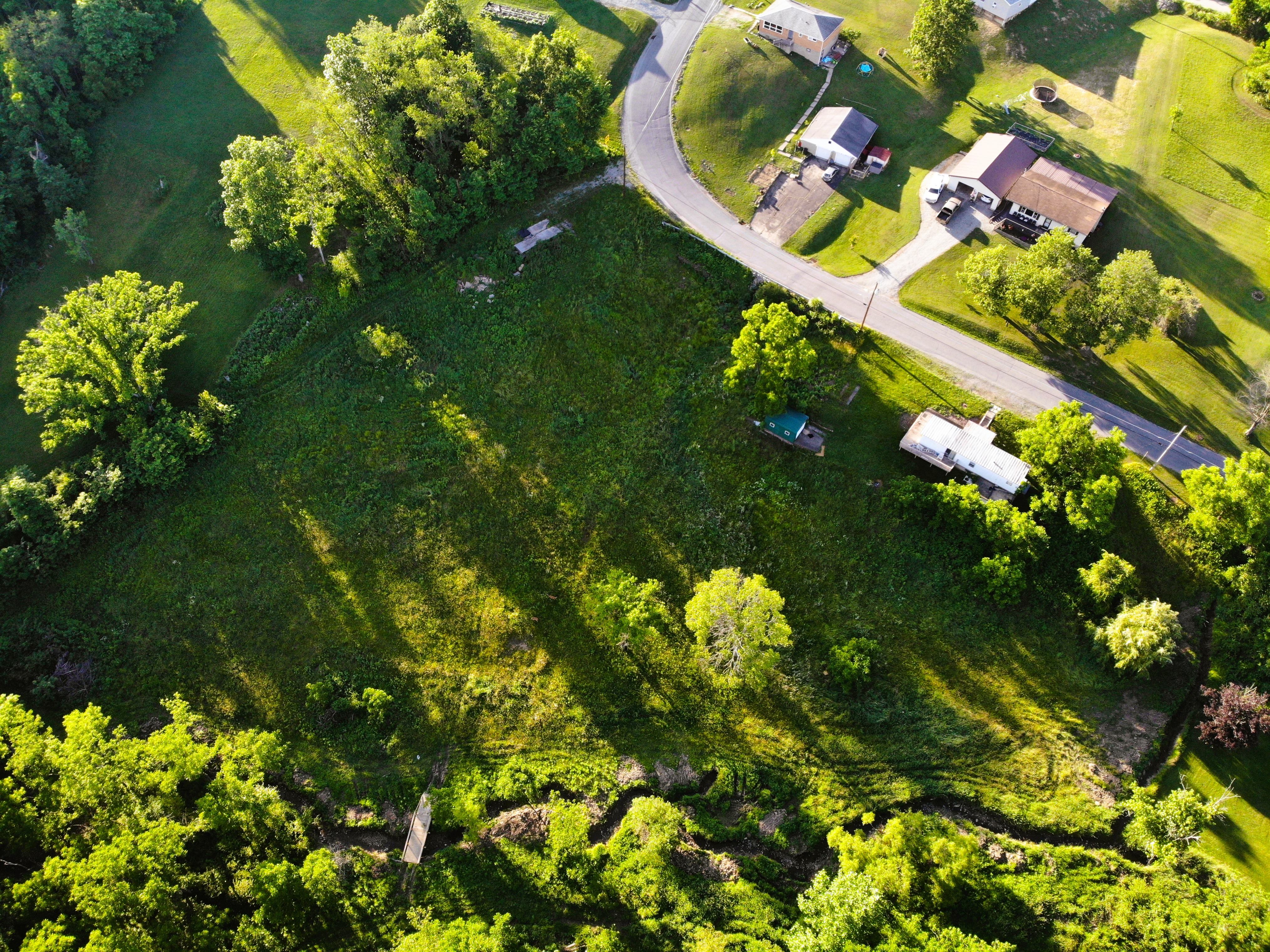 Aerial drone view of a wooded land parcel beside a country road